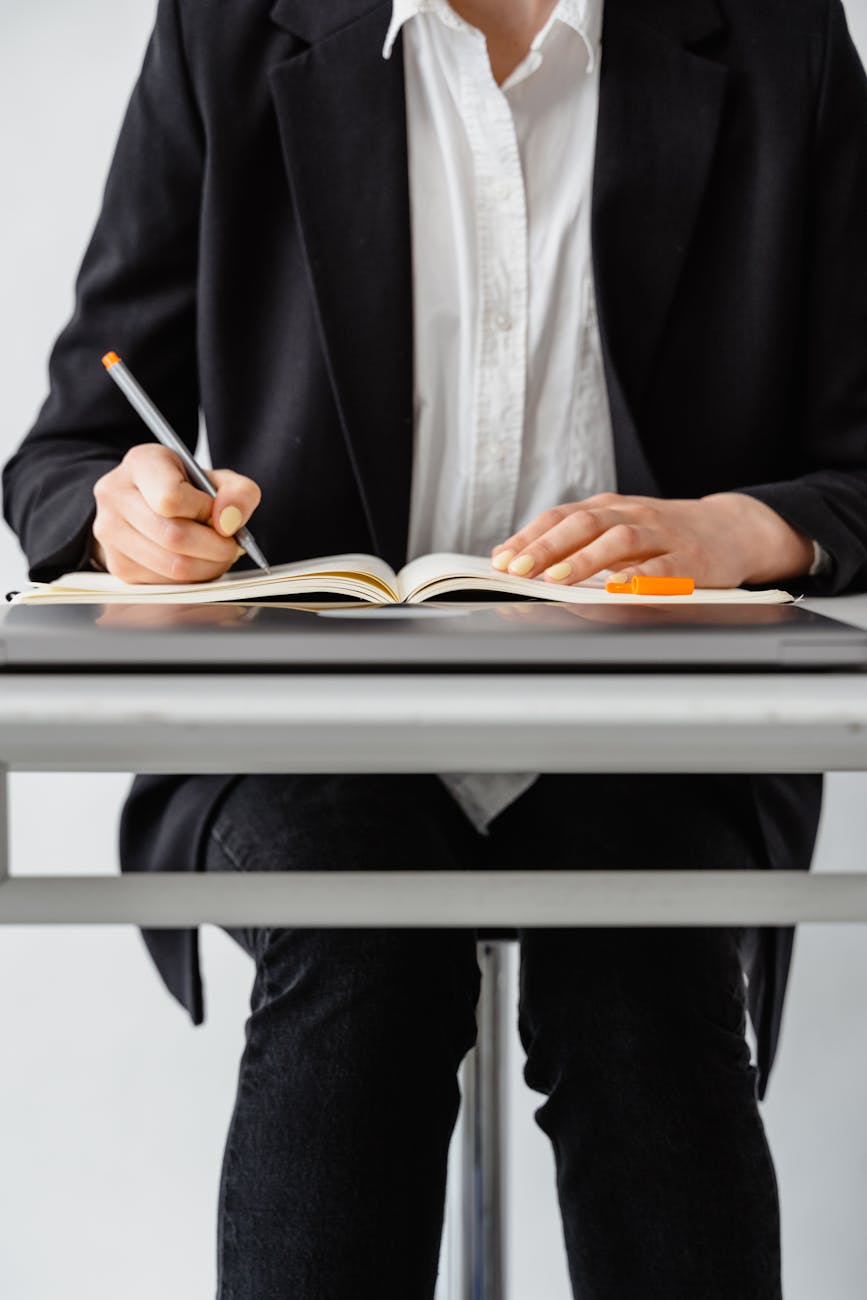 person in black suit jacket writing on white paper